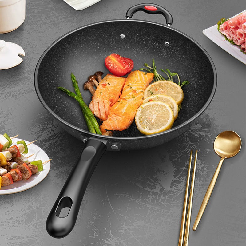Wok med stegte laksestykker, asparges, svampe og citronskiver på et gråt bord med grillspyd og spisepinde